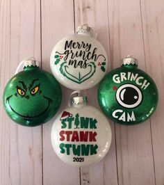 three christmas ornaments are hanging on a white wooden wall, one is green and the other is red