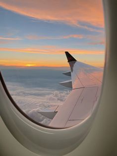 the wing of an airplane as it flies above the clouds at sunset or dawn in the sky