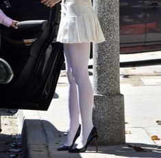 a woman in white is getting out of a car with her hand on the door