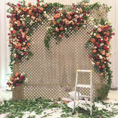 a ladder sitting in front of a flower covered wall with flowers on it's sides