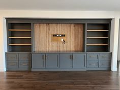 an entertainment center with built - in cabinets and cupboards on one side, wood paneling on the other