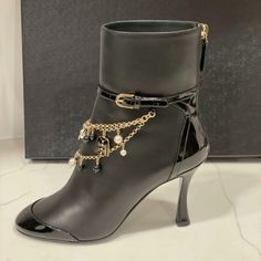 Chanel 2020 (20a Season) Lambskin Leather Ankle Booties Have A Tonal Patent Leather Cap Toe And Back And 3.25" Curved Patent Leather Heel. Patent Leather Wrap Around Belt With Goldtone Buckle. Rows Of Goldtone Chains With Multiple Charms (Camellia, Cc, Pearls, Blazer Adorn The Front. Padded Leather Insole. Leather Sole. Back Zip. Shaft: 5.5". Made In Italy. Designer Color: Black. Size: 36 Eu (Insole: 9 1/8") Typically Chanel Shoes Run Small. Brand New With The Box. Luxury Evening Ankle Strap Boots, Elegant Formal Boots With Chain Strap, Formal High Heel Boots With Chain Strap, Evening High Heel Boots With Chain Strap, Elegant Ankle-high Heeled Boots, Chanel Ankle Boots, Square Toe Ankle Boots, Cap Toe Boots, Sock Ankle Boots