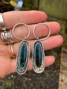 These beautiful pieces of opalized wood are set in sterling silver with a textured and patina'd setting. They will be finished with handmade 1mm sterling silver ear wires.   They measure 61 mm from the top of the hoop to the bottom of the settings. Each piece weighs 6.8g  Colours may vary slightly depending on screen settings. This is a finished piece and cannot be altered. However feel free to message me with any questions or for custom orders. Silver Smithing Jewelry, Opalized Wood, Wood Hoop Earrings, Fantasy Earrings, Silversmith Jewellery, Custom Jewellery, Engagement Earrings, Vintage Jewelry Necklace, Snake Jewelry