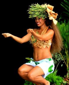 a woman in a hula skirt dancing with grass on her head and hands behind her back