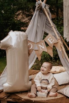 a baby sitting in front of a teepee tent