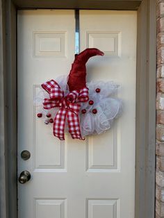 a red and white wreath on the front door of a house that is decorated with gingham