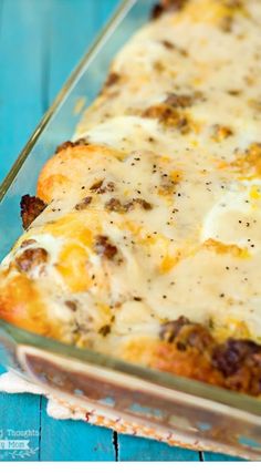 a casserole dish with cheese and meat in it sitting on a blue table