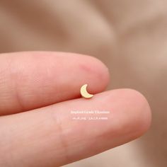 a person's finger with a tiny yellow crescent ring in the shape of a half moon