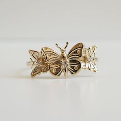 "With brave wings, she flies..."The "Butterfly Hope ring" ring is inspired by the beauty and endurance of butterflies. It symbolizes personal transformation, hope, and rebirth. Three gold butterflies sit on a 14K solid gold band, embellished with your choice of tiny white diamonds. Handcrafted in 14K solid yellow gold, rose gold and white gold. 14K solid gold Natural round white diamonds. SI clarity. Approx 0.035ct 1.2mm ring band **This item is specially made for you. Please allow 1-2 week lead Gold Butterfly Ring In Fine Jewelry Style, Gold Butterfly Charm Ring, Butterfly Charm Ring For Anniversary, Fine Jewelry Yellow Gold Butterfly Ring, Gold Butterfly Ring With Charm, Gold Butterfly Ring With Butterfly Charm, Gold 14k Butterfly Shaped Ring, Gold 14k Butterfly Ring, 14k Gold Butterfly Ring For Anniversary