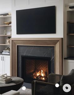 a living room with a fire place in the middle and a flat screen tv above it