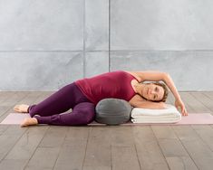 a woman is doing yoga on a mat with her arms behind her head and legs crossed