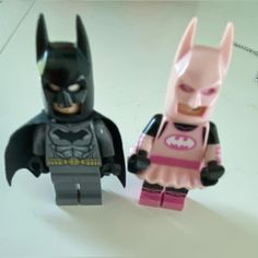 two lego batman minifigures standing next to each other on a white surface