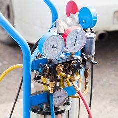 an air compressor with gauges and valves attached to it's back end in front of a white car