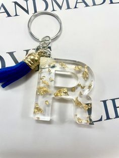 the letter b is made out of clear acrylic and has a blue tassel