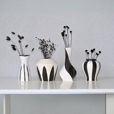 four white vases are lined up on a table