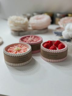 three small cupcakes with raspberries in them on a white counter top