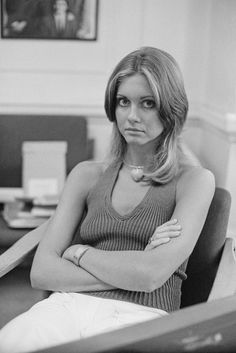 a black and white photo of a woman sitting in an office chair with her arms crossed