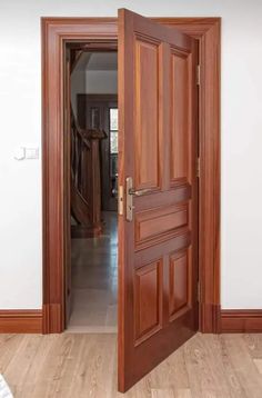 an open wooden door in the middle of a room with white walls and wood floors