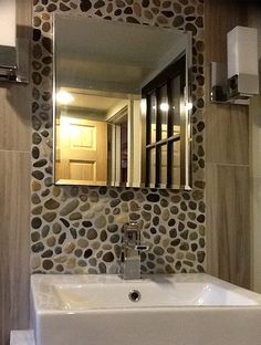 a white sink sitting under a bathroom mirror next to a wall mounted faucet