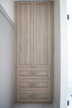 an empty closet with wooden drawers and white tile flooring in a home bathroom area