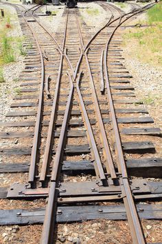 an old train is going down the tracks in the middle of some grass and dirt