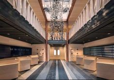 an empty lobby with benches and chandelier in the center, surrounded by large windows