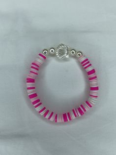 a pink and white beaded bracelet with two silver beads on the end, sitting on a white surface