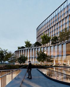 a man standing on the edge of a walkway next to a building with glass windows