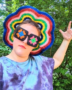 a person wearing sunglasses and a crocheted hat with the shape of a flower