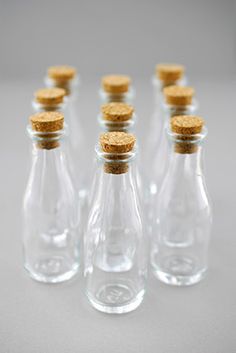 six small glass bottles with corks on the top and bottom, lined up in a row