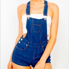 A Pair Of Denim Overall Shorts Featuring A Square Neckline, Front Bib Pocket, Adjustable Shoulder Straps, Dropped Armholes, Traditional Five-Pocket Construction, Belt Loops, Side Buttons, And Racerback Details Category: Rompers Color Dark Denim Fabric: 45% Cotton, 30% Rayon, 23% Polyester, 2% Spandex Content: 45% Cotton, 30% Rayon, 23% Polyester, 2% Spandex Sm4-6 Med8-10 Lg 12-14 Street Wear Style Basic Capsule Trendy Chic Dress Down Extra Stretch Comfortable Lounge Casual Vacation Travel Outfit Trendy Short Denim Jumpsuit With Pockets, Medium Wash Short Length Overalls With Pockets, Short Length Medium Wash Overalls With Pockets, Denim Shortalls With Pockets In Dark Wash, Denim Blue Shortalls With Pockets, Denim Overalls With Pockets In Short Length, Denim Overalls With Pockets Short Length, Short Denim Overalls With Pockets, Dark Wash Denim Shortalls With Pockets