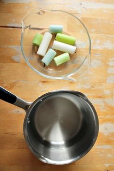 an aluminum pan with cut up apples in it on a wooden table next to a glass bowl