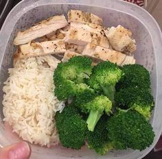 a plastic container with rice, broccoli and chicken on it in someone's hand