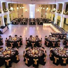 a banquet hall with tables and chairs covered in black cloths, decorated with candles