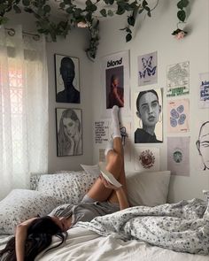 a woman laying on top of a bed in a room with pictures hanging above her head