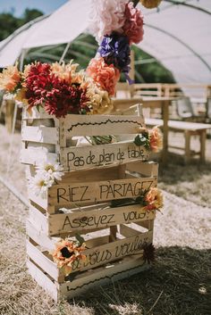 a wooden crate filled with flowers sitting on top of a grass covered field next to a white tent