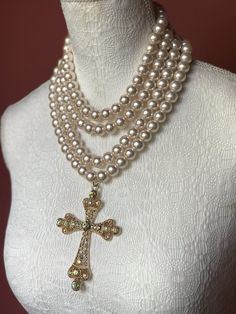 Multi strand pearl necklace with Baroque style cross. Make a statement wearing this unique piece. 4 strands of 12mm glass pearls. Please choose pearl colour from drop. down menu. Each strand has its own clasp, so that you can wear the strands individually or grouped as you like! Materials used are: 12mm glass pearls with coating. Cross is zinc alloy with iridescent glass crystals. Mannequin is wearing cream rose pearls. RETURNS EXCHANGES REFUNDS Returns, exchanges or refunds are accepted for may Elegant Cross Pendant Necklace With Pearl Drop, Elegant Pearl Drop Cross Pendant Necklace, Elegant Pearl Cross Necklace With Pearl Drop, Elegant Pearl Necklace With Cross Pendant, Elegant White Cross Necklace With Pearl Pendant, Elegant Cross Necklace With Pearl Drop, Elegant White Cross Necklace For Wedding, White Cross Necklace For Party, Elegant Cross Necklace With Pearl Chain