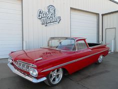 an old red car parked in front of a building