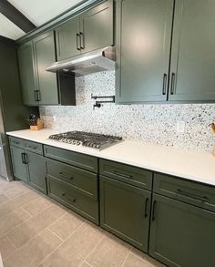 a kitchen with green cabinets and white counter tops