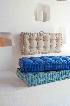 two blue and white pillows sitting next to each other on top of a shelf in a room