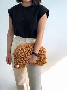 a woman in white pants holding a brown purse with curly hair on it's side