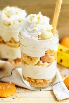 two jars filled with desserts sitting on top of a wooden table next to bananas