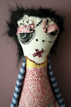 an image of a doll with black hair on it's head and eyes, wearing a striped dress