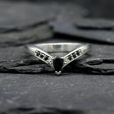 a black diamond ring sitting on top of a rock