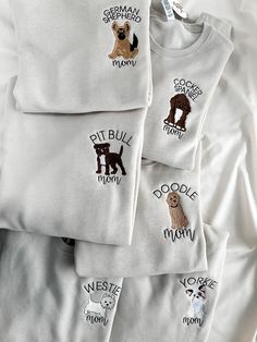 three white shirts with embroidered dogs on them