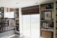 a living room filled with furniture and bookshelves next to a window covered in blinds