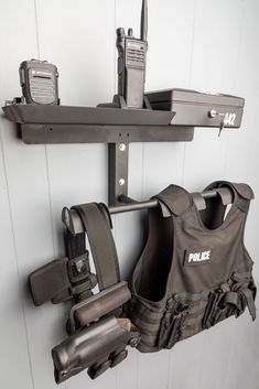 two police vests hanging on a wall with other items attached to the wall behind them