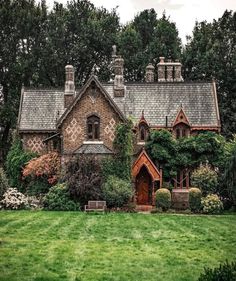 an old house with ivy growing all over it's roof and windows, surrounded by lush green grass