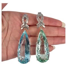 "These vintage earrings feature two stunning pear-shaped aquamarines with a combined weight of 122.8 carats, showcasing a mesmerizing blend of blue and green hues. They are elegantly accented with 0.42 carats of diamonds, enhancing their timeless appeal and beauty." aqamarines are natural no heat Luxury Light Blue Fine Jewelry Earrings, Luxury Aquamarine Fine Jewelry, Luxury Aquamarine Teardrop Jewelry, Blue Aquamarine Earrings Fine Jewelry, Luxury Blue Aquamarine Earrings, Luxury Aquamarine Faceted Jewelry, Green Aquamarine, No Heat, Aquamarine Earrings