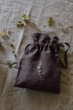 a small bag sitting on top of a bed covered in leaves and flowers next to a cloth pouch